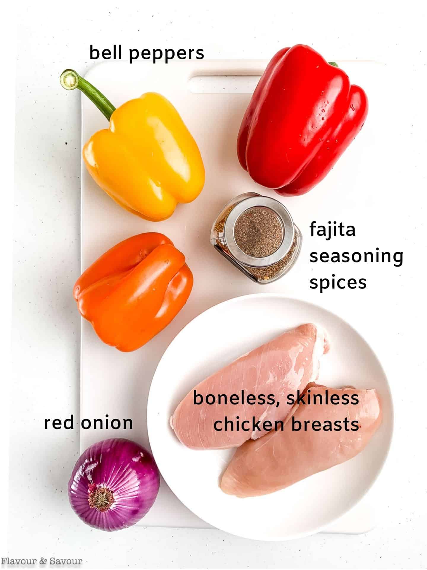 A labeled photo of ingredients for Air Fryer Chicken Fajitas: bell peppers, red onion, fajita seasoning, boneless skinless chicken breasts.