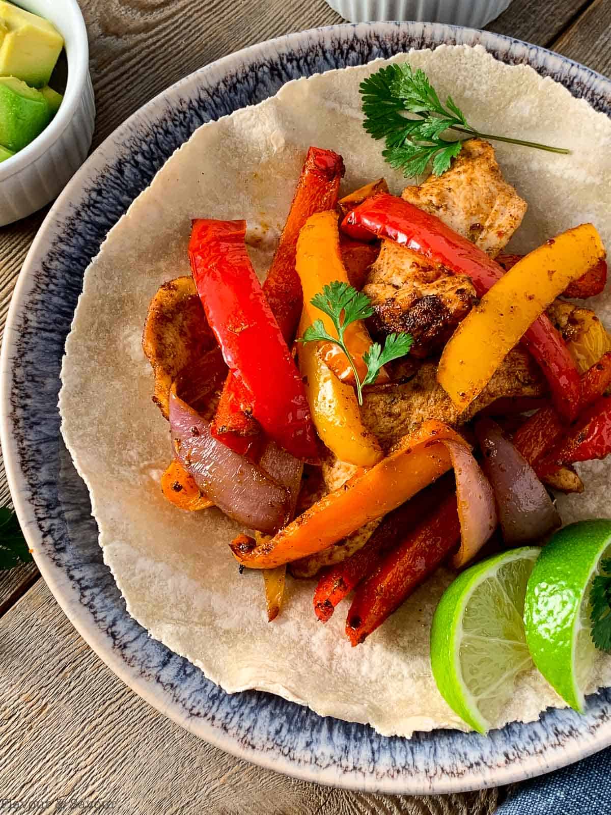 Close up view of chicken fajita on a tortilla.