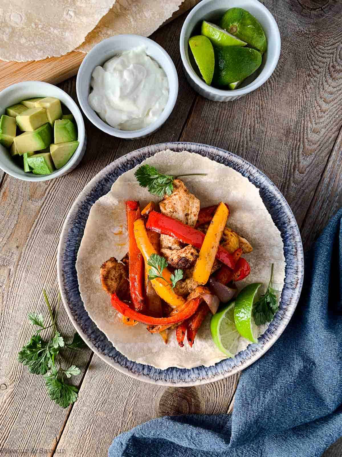 Air Fryer Chicken Fajitas with avocado, sour cream and lime wedges