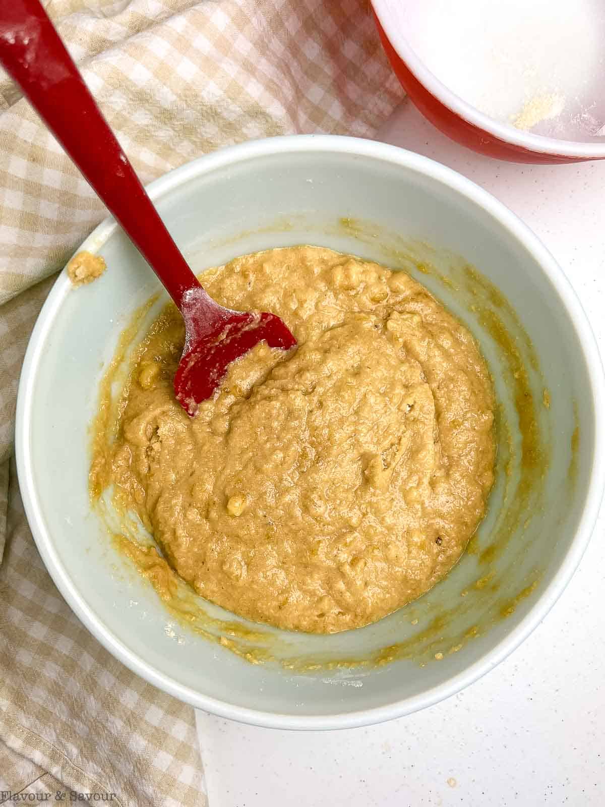 Wet and dry ingredients for gluten-free banana coffee cake combined in a bowl.