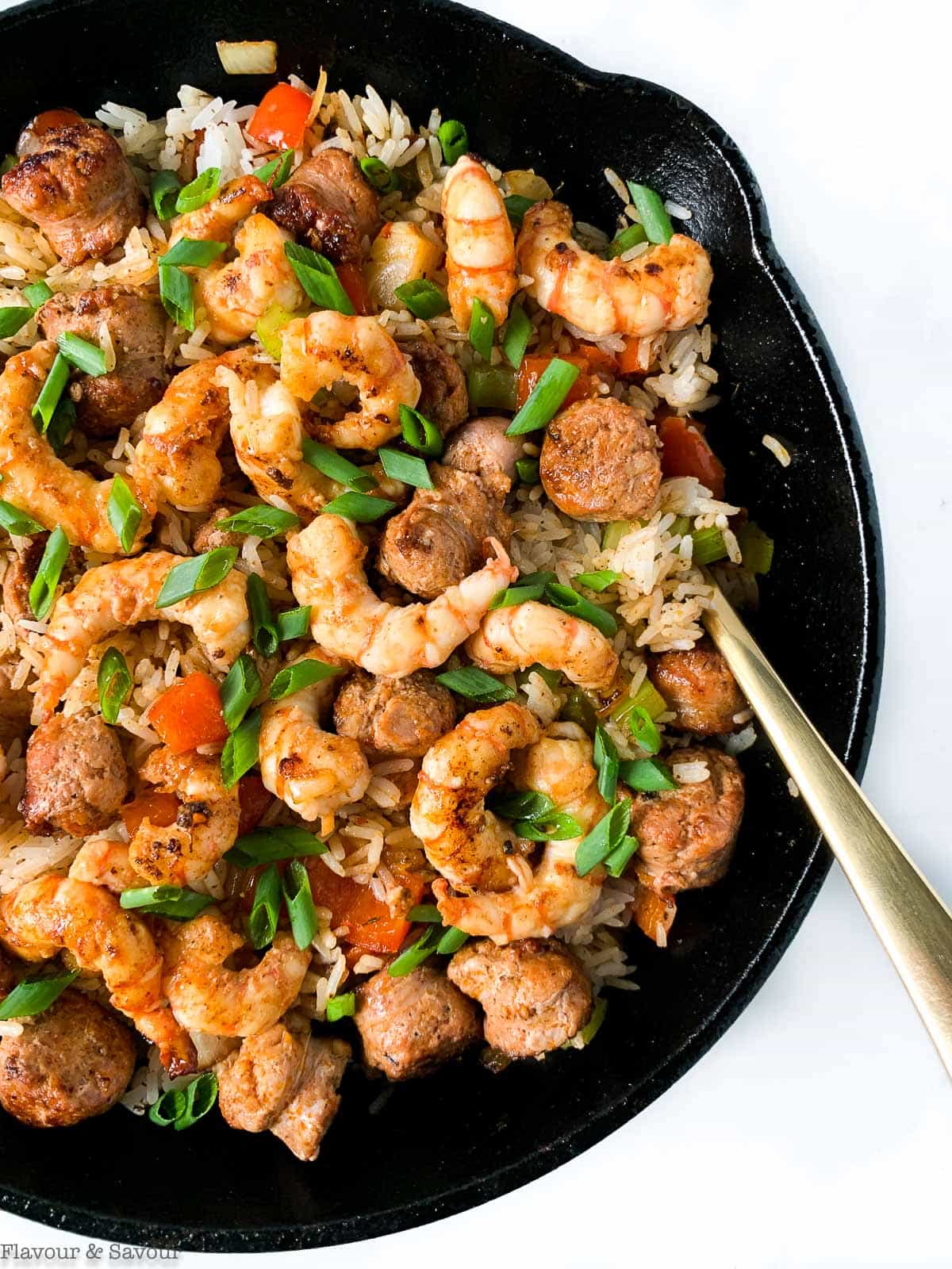 A cast iron skillet with Cajun Shrimp Fried Rice garnished with snipped green onions.