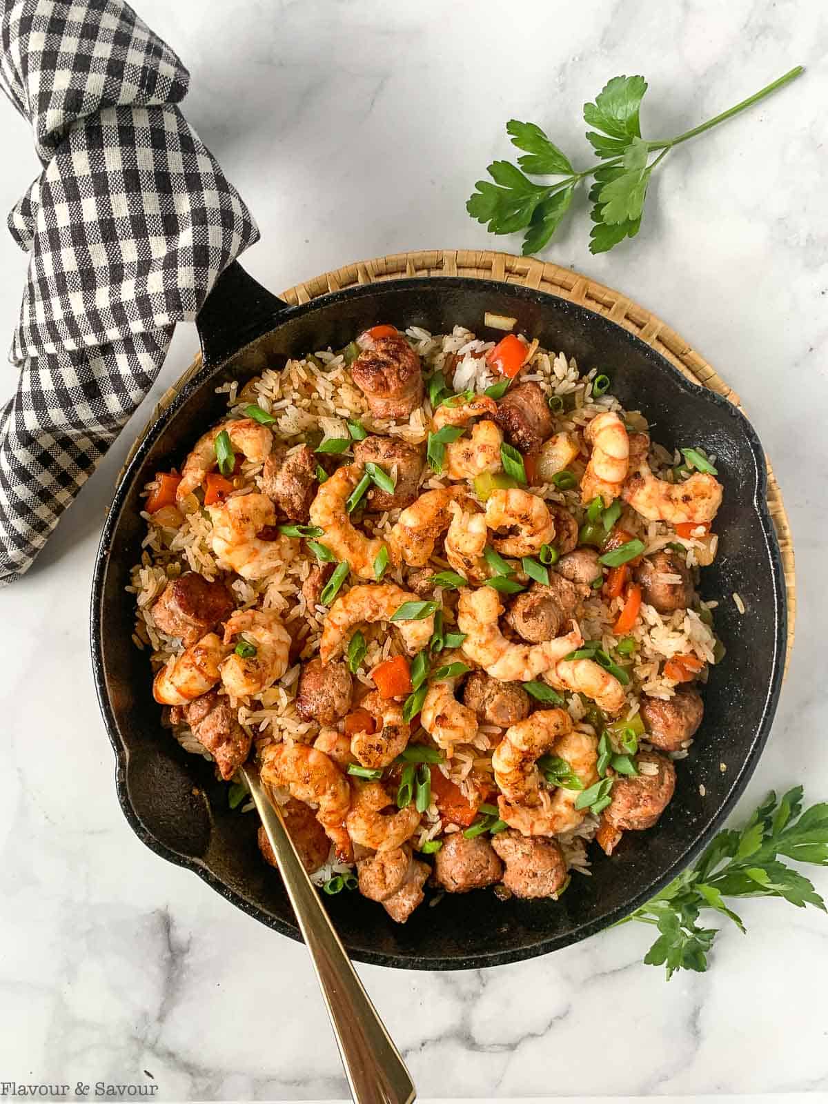 A cast iron skillet with Cajun Shrimp Fried Rice with a towel around the handle.