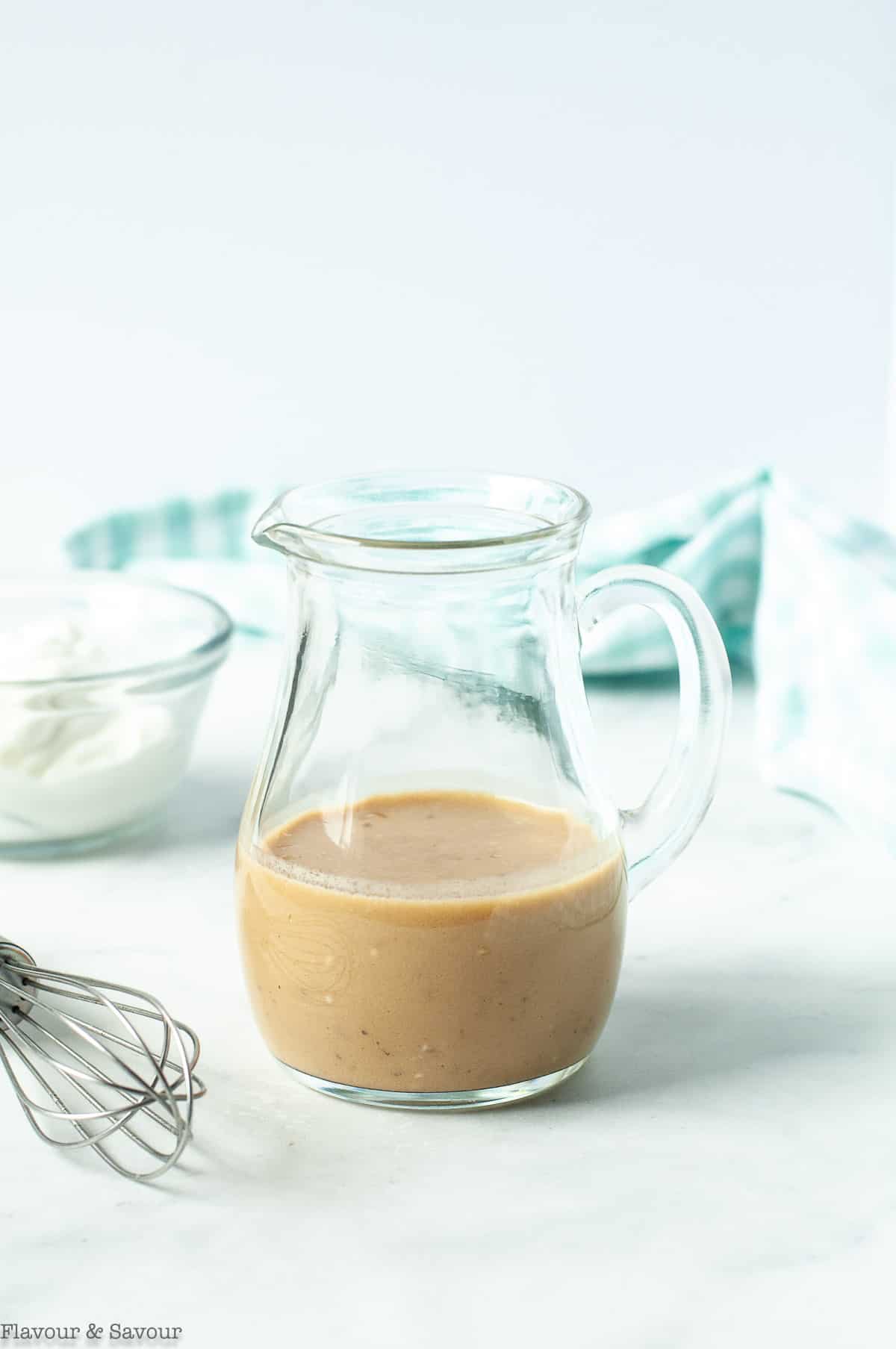 Creamy Maple Balsamic Dressing in a small pitcher with a whisk