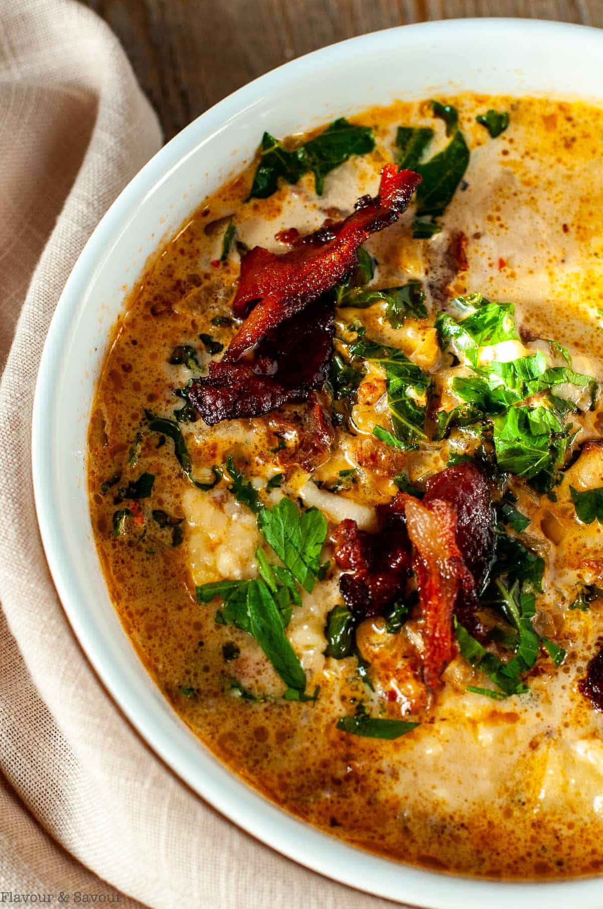 Close up view of a bowl of Tuscan sausage, potato and kale soup.