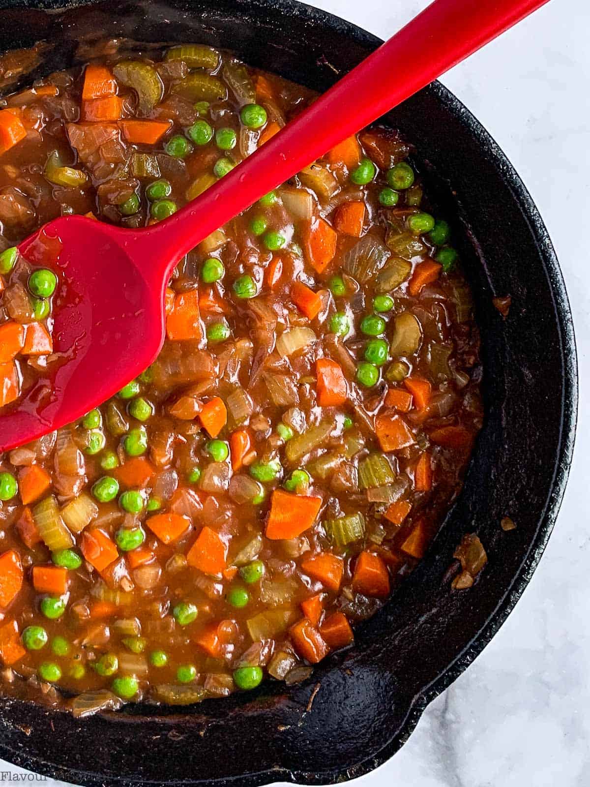 Easy Homemade Shepherd's Pie filling in a cast iron skillet with a red spatula