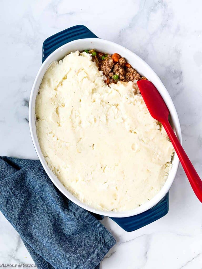 Spreading mashed potatoes on shepherd's pie filling