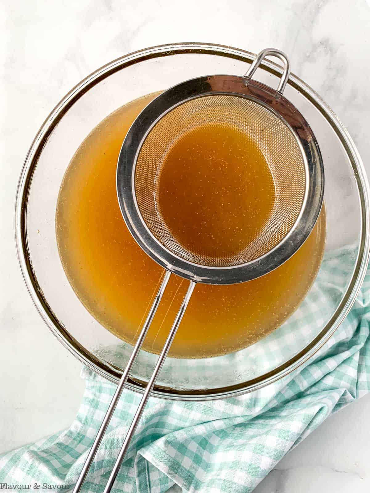 Straining the broth through a fine mesh strainer.