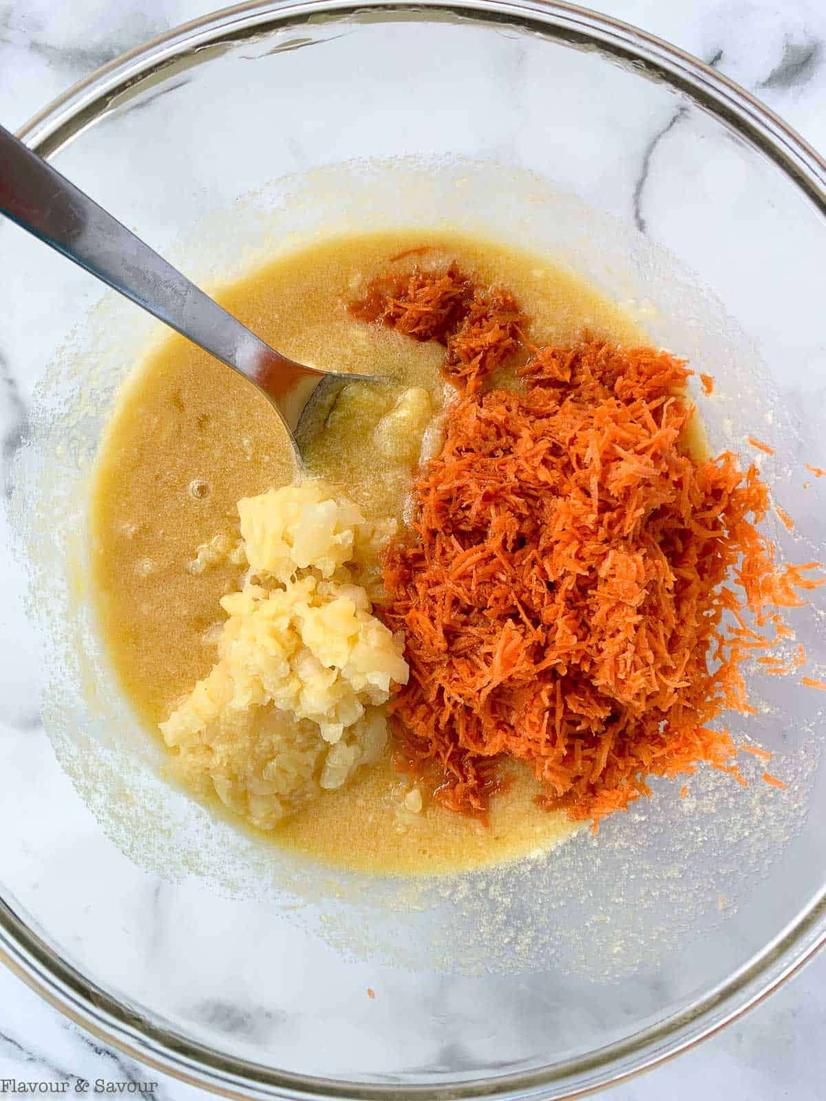 Adding pineapple and grated carrots to a bowl with eggs and sweetener.