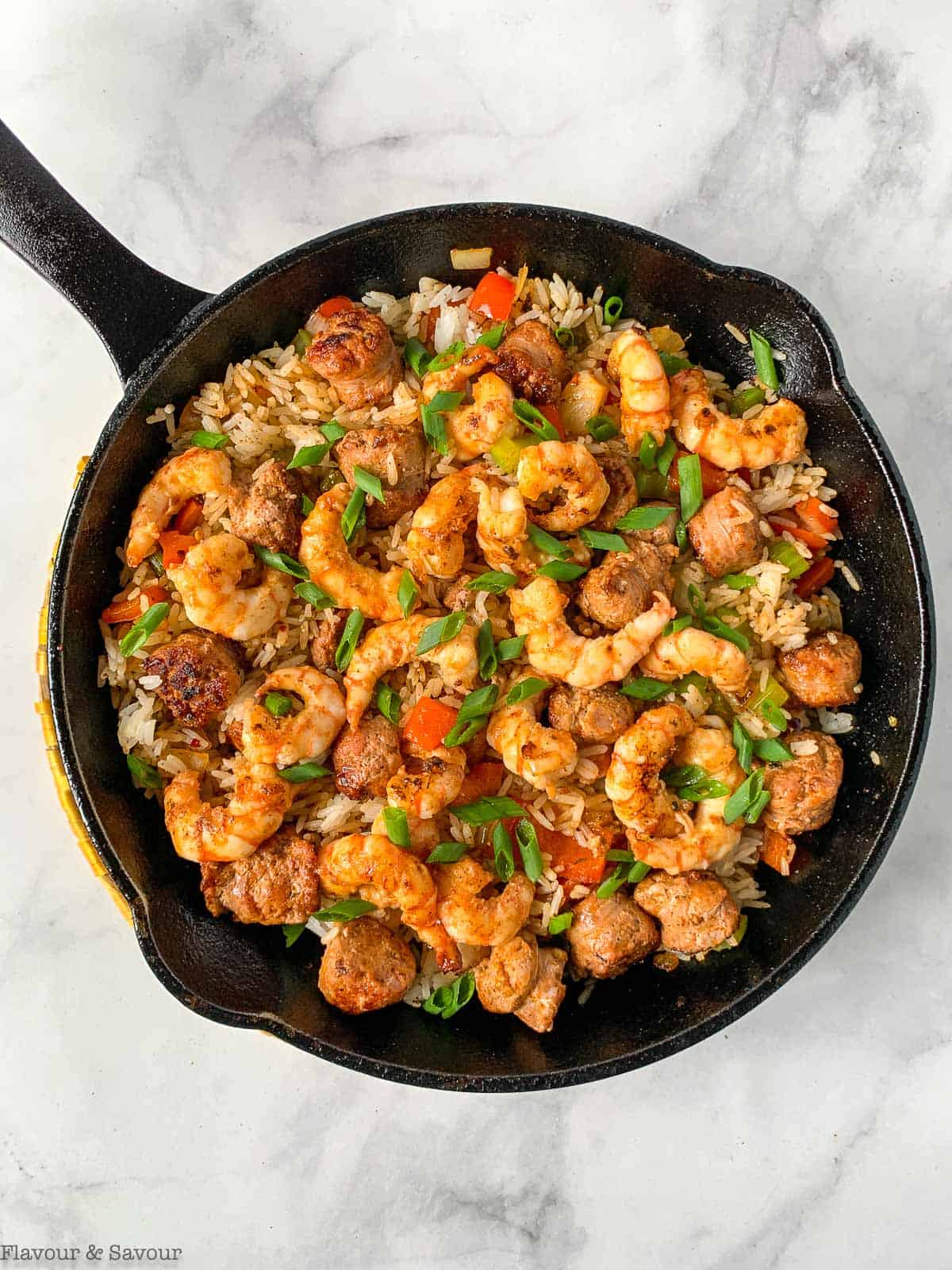 Adding rice, shrimp and sausage to a skillet to make Cajun shrimp fried rice.