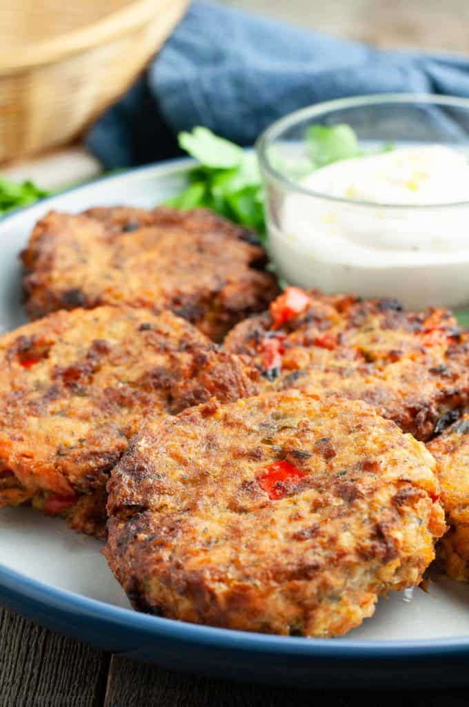 Close up view of salmon patties cooked in an air fryer on a plate with lemon aioli