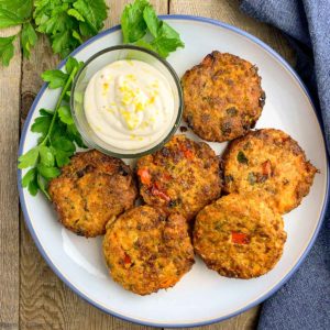Salmon Patties on a round plate with a bowl of aioli, overhead view