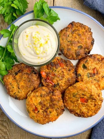 Salmon Patties on a round plate with a bowl of aioli, overhead view