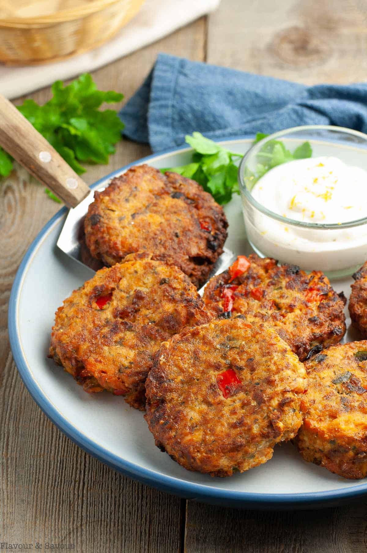 Air Fryer Salmon Patties on a round plate with a bowl of lemon aioli