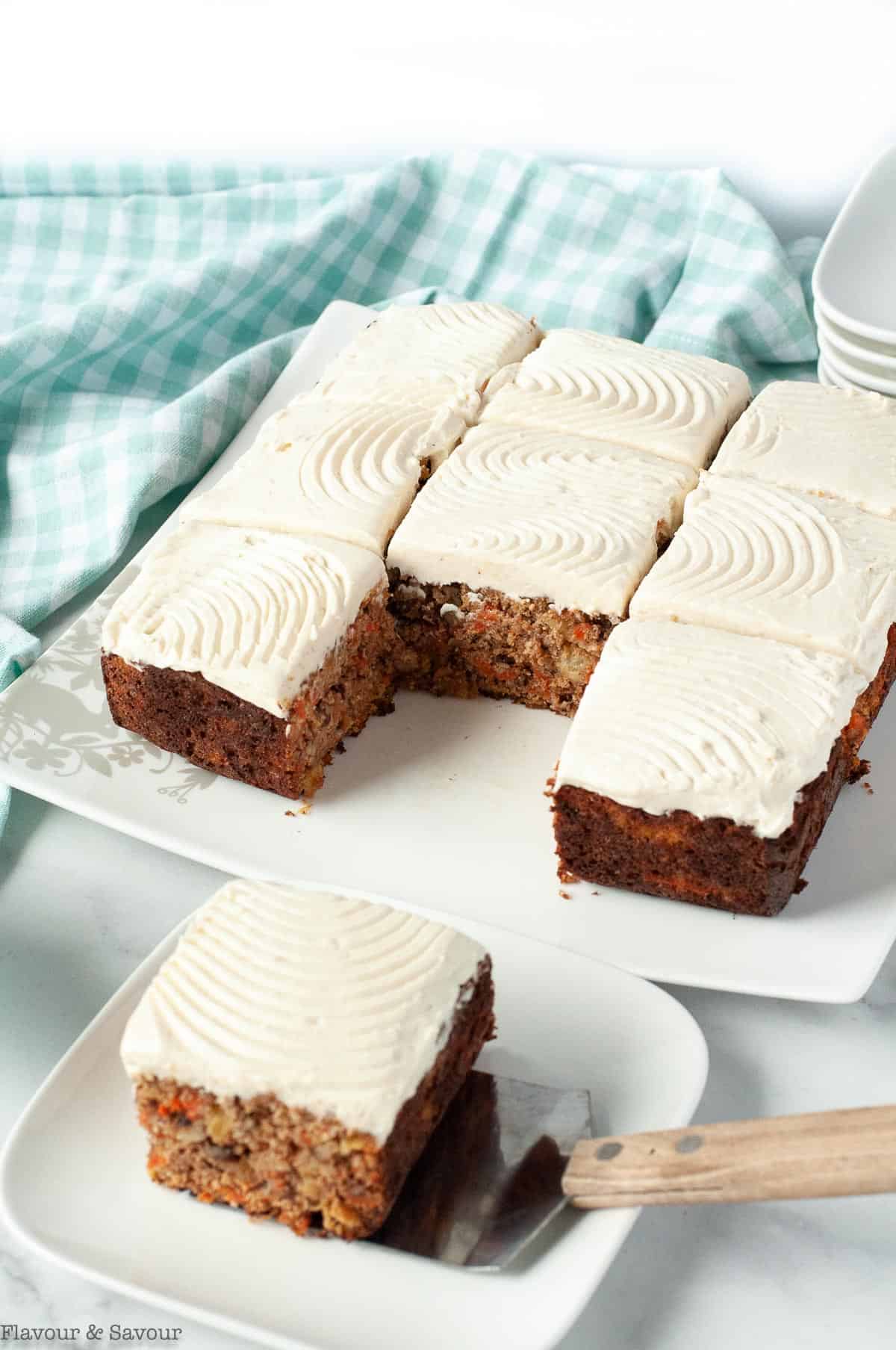 An 8-inch square grain-free carrot cake with maple cream cheese frosting with one slice removed