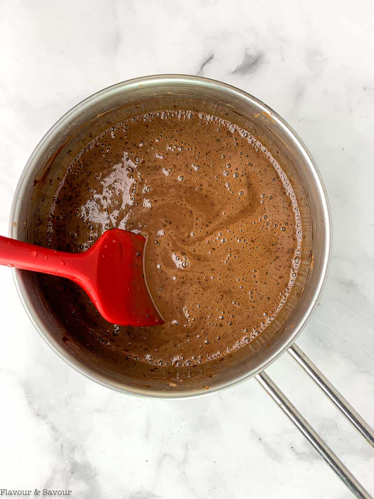 Chocolate pudding in a saucepan with a spatula.