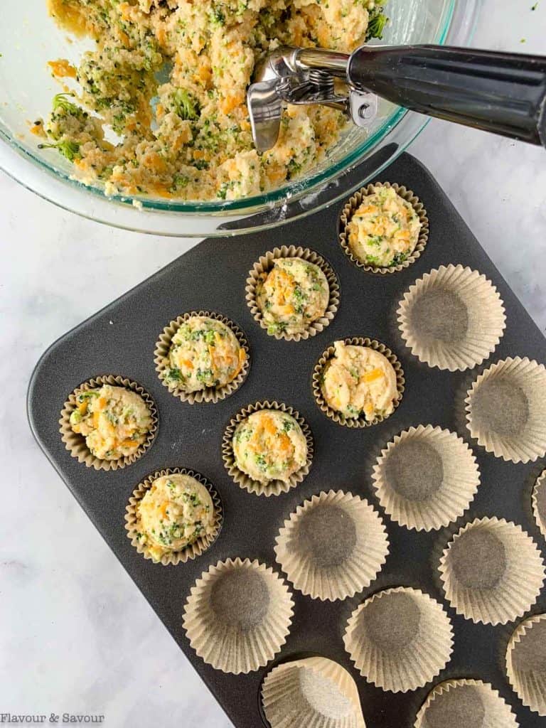 Filling muffin cups with muffin batter.