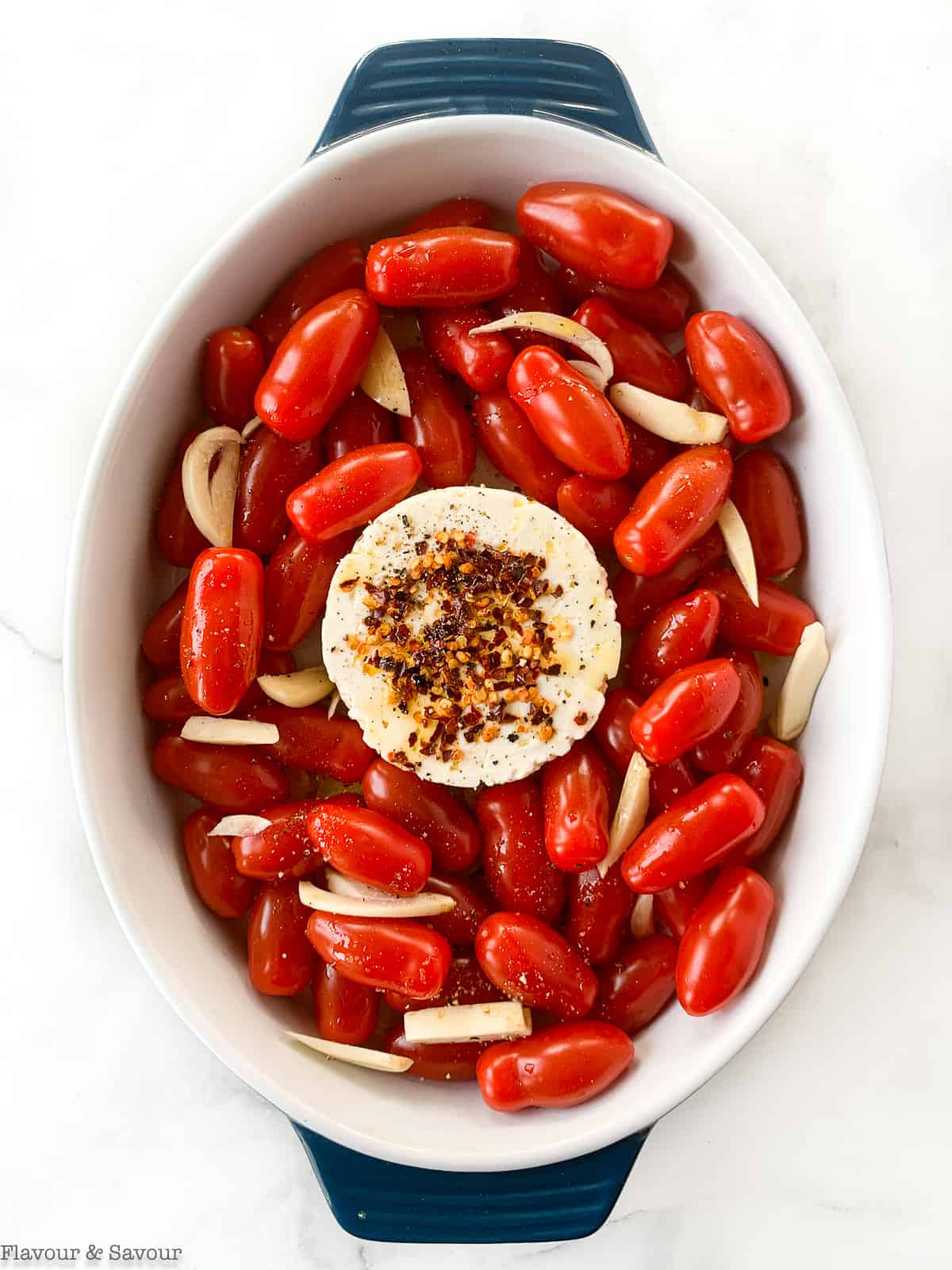 Feta cheese with tomatoes and garlic in a baking dish.