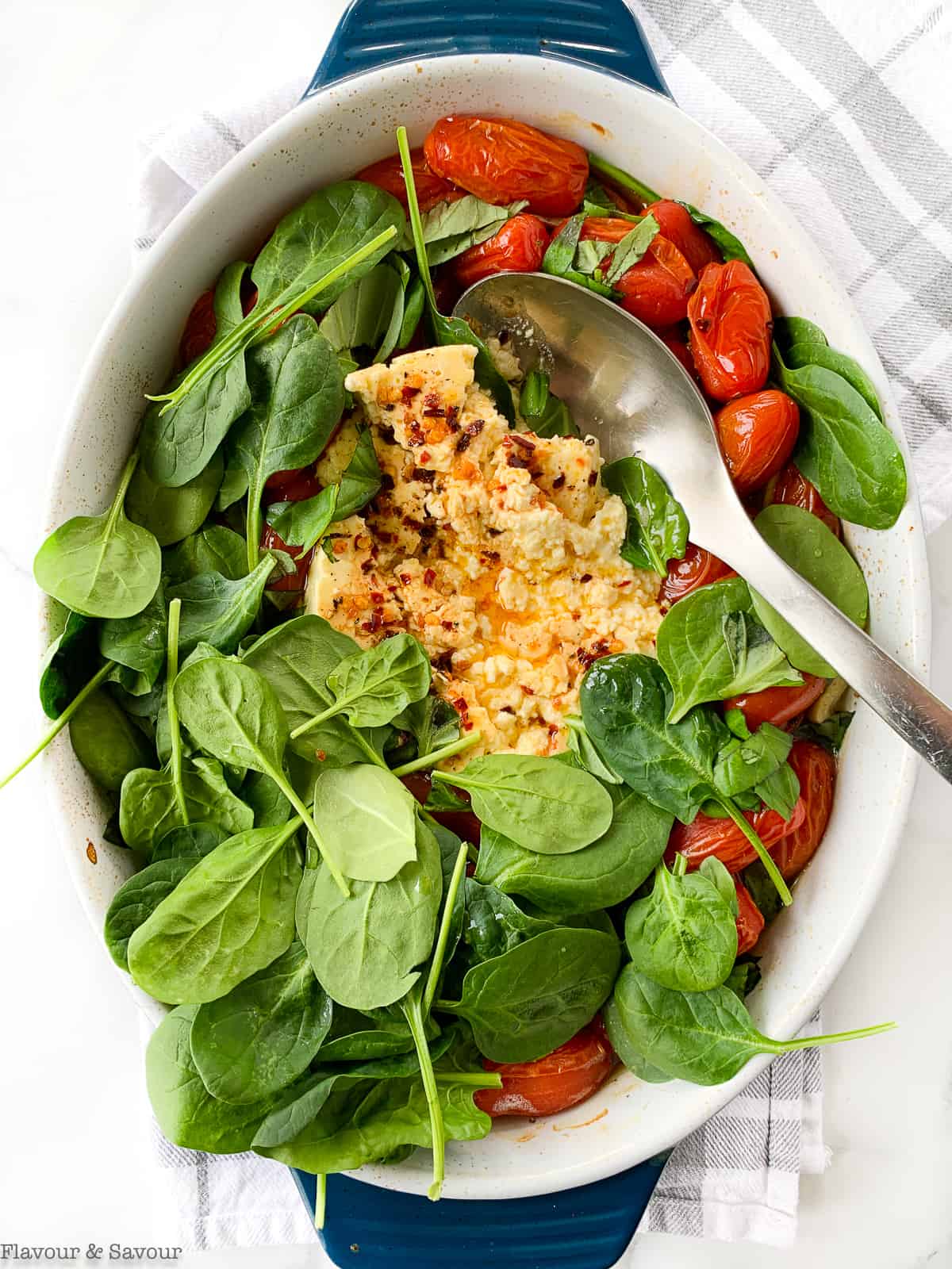 Adding spinach to feta pasta bake.