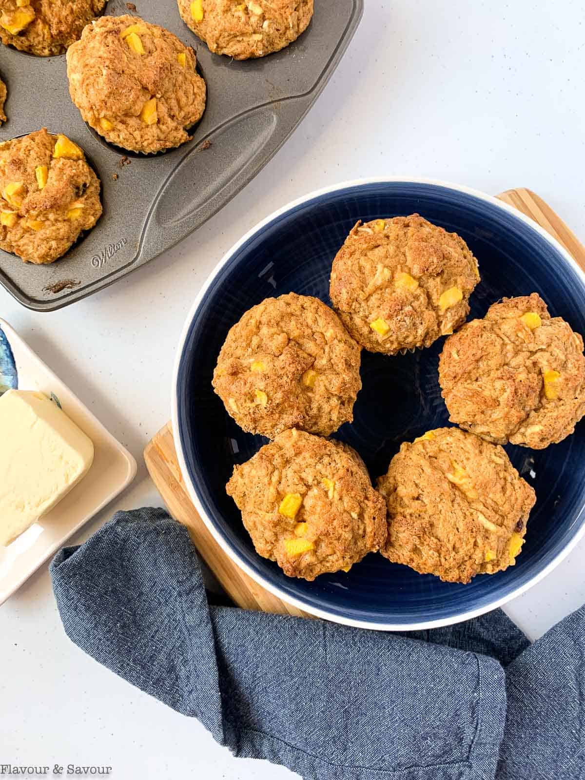 Gluten-free Mango Muffins in a bowl with a butter dish beside