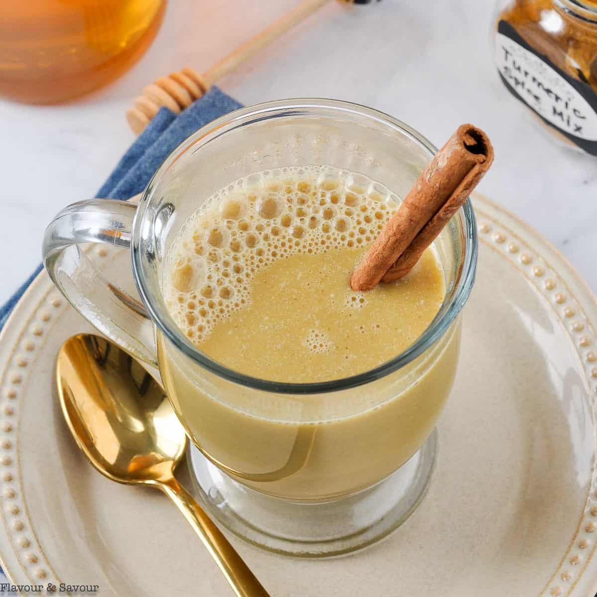 Overhead view of a mug of warm turmeric cinnamon milk with a cinnamon stick.