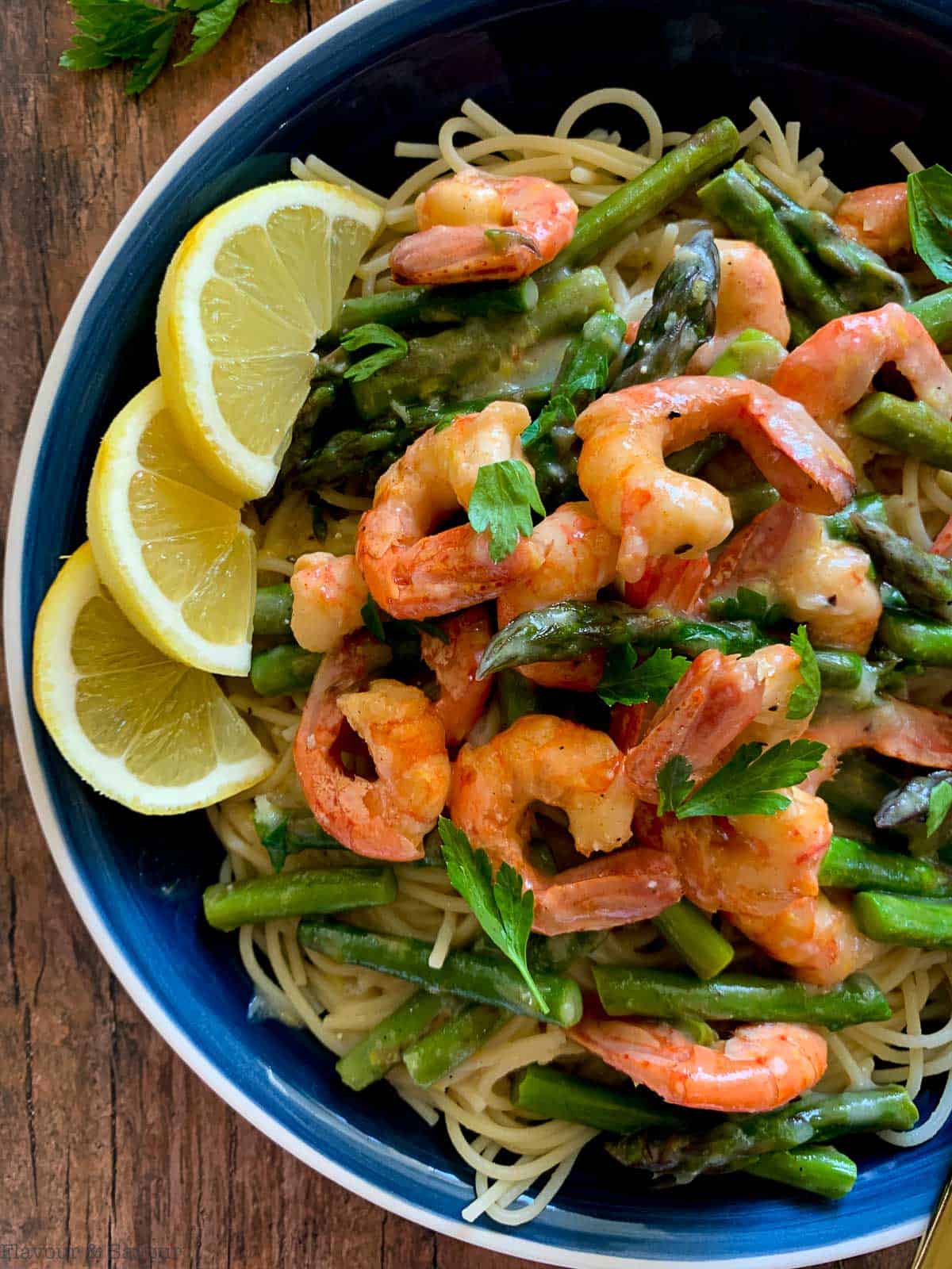 a large bowl of shrimp linguine with asparagus and lemon