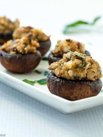 Mushrooms stuffed with blue cheese, garlic and herbs on a white narrow serving dish