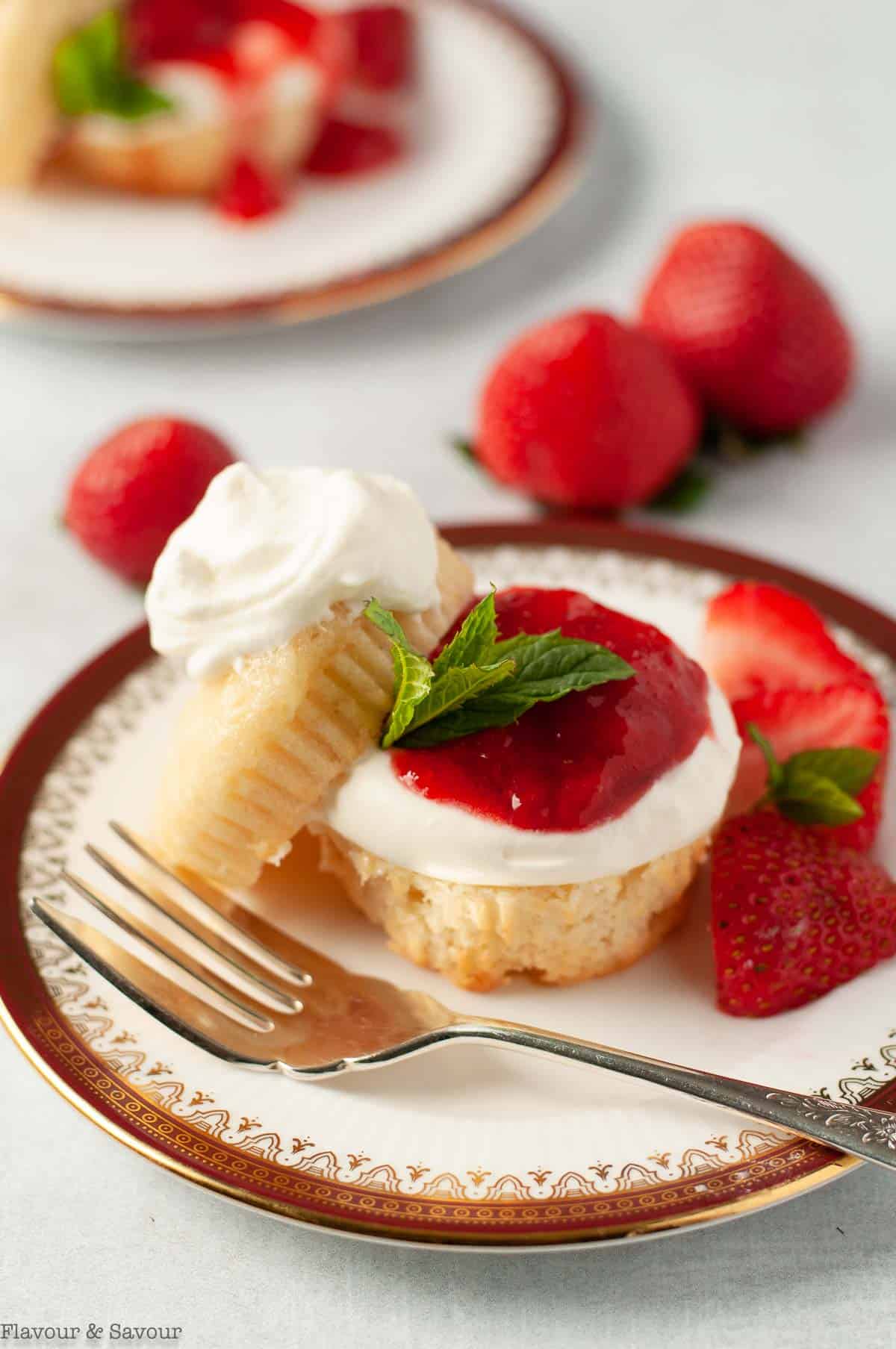 Close up view of a strawberry shortcake garnished with whipped cream and mint.