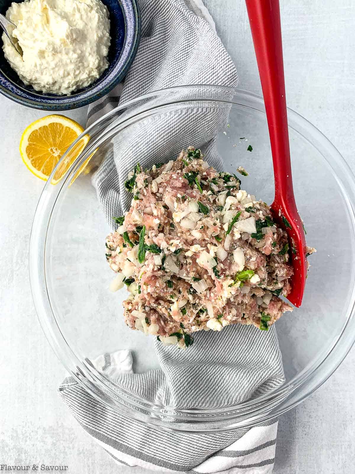 Ingredients for Greek Chicken Burgers with Spinach and Feta in a glass bowl with a spatula