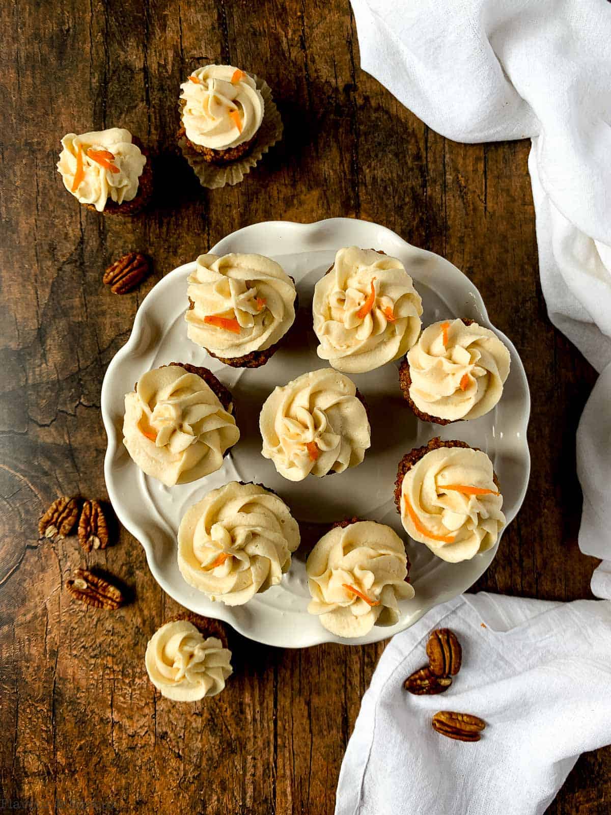 mini carrot cake cupcakes with cream cheese frosting on a white plate.