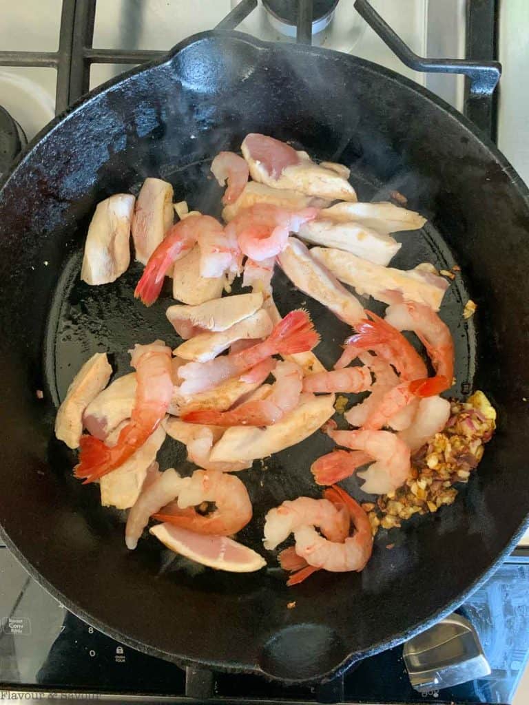 Chicken and shrimp in a cast iron pan.
