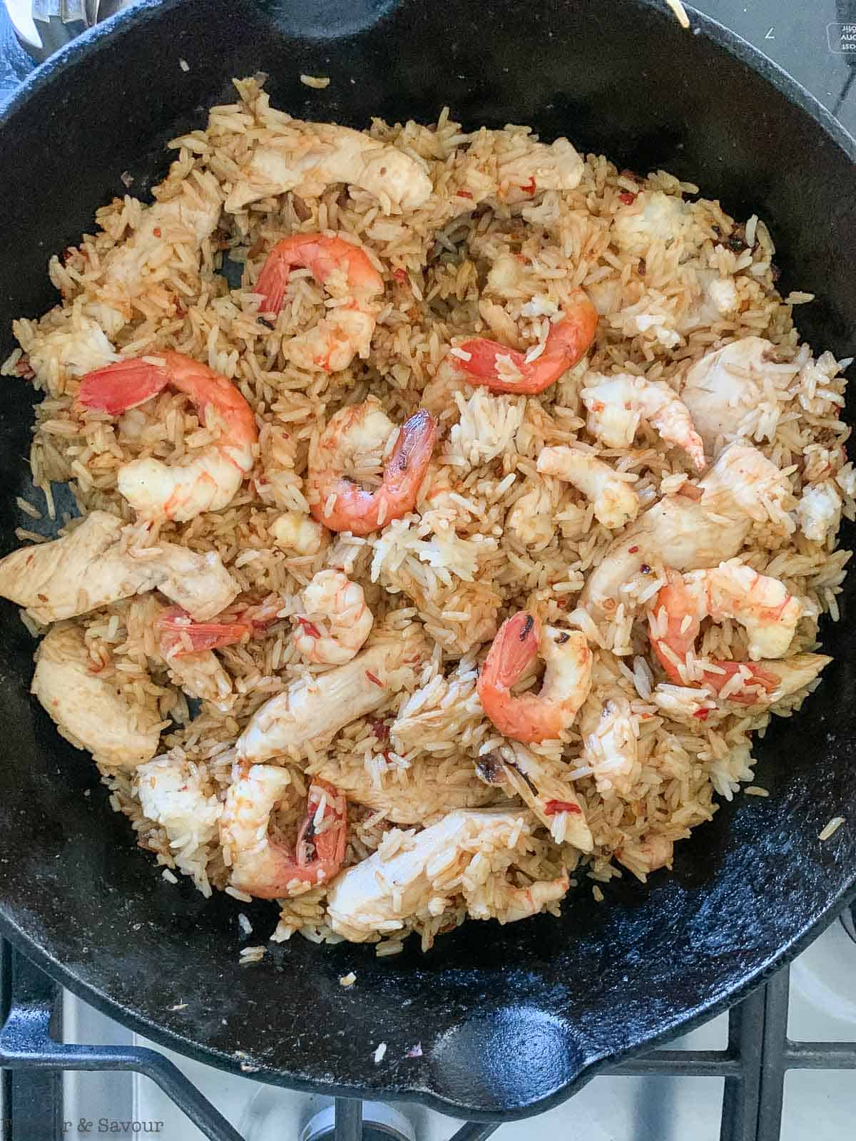 Adding seasoning to nasi goreng.