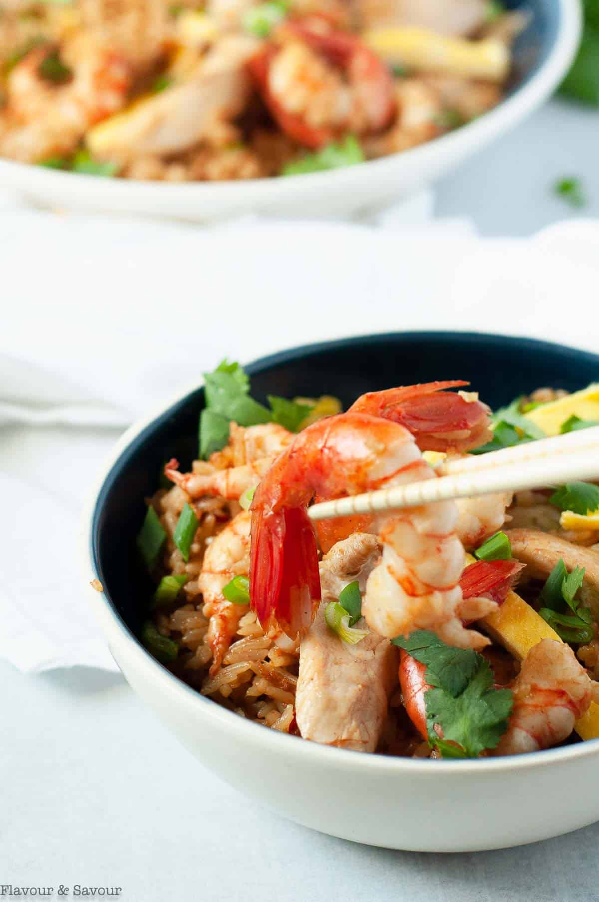 Close up view of a prawn with chopsticks from a bowl of Nasi Goreng