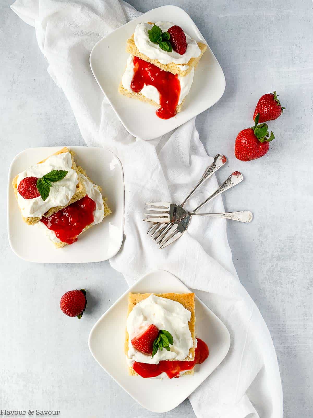 Overhead view of 3 plates of Keto Strawberry Shortcake with strawberry sauce and fresh berries