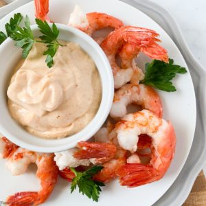 Shrimp on a plate surrounding a bowl of dip