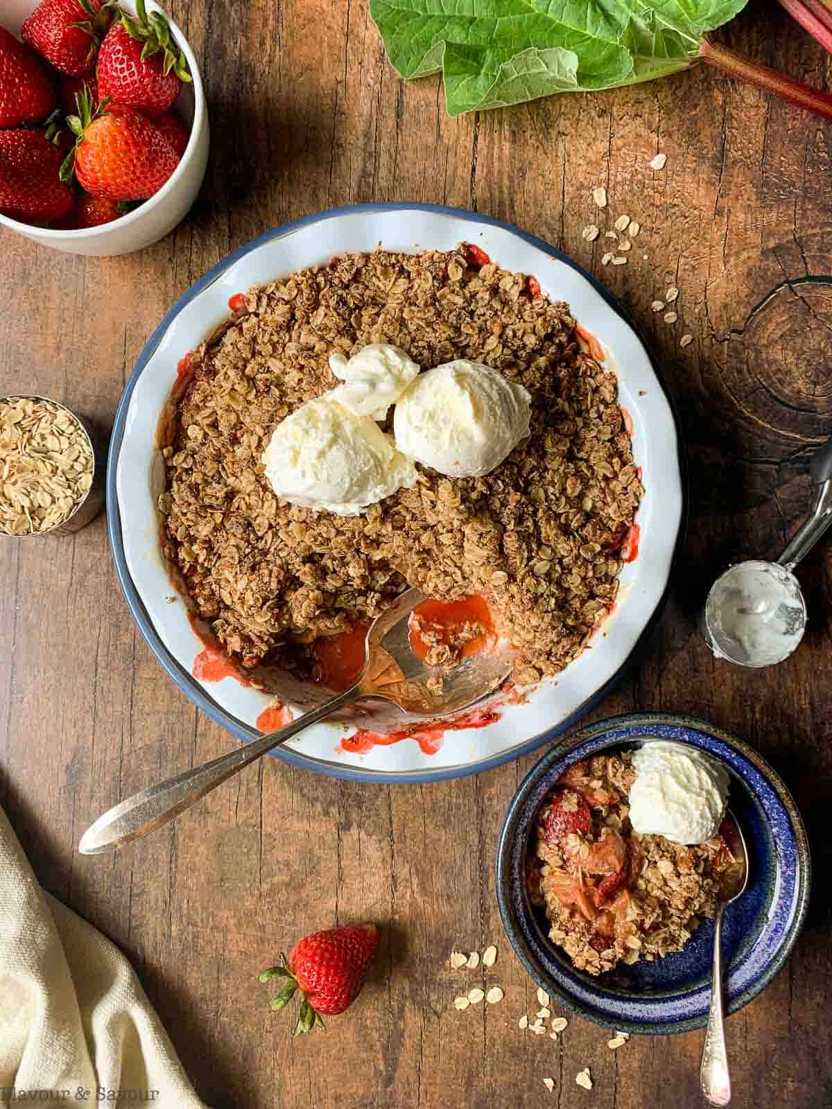 Overhead view of Strawberry Rhubarb Crisp with ice cream and fresh strawberries.