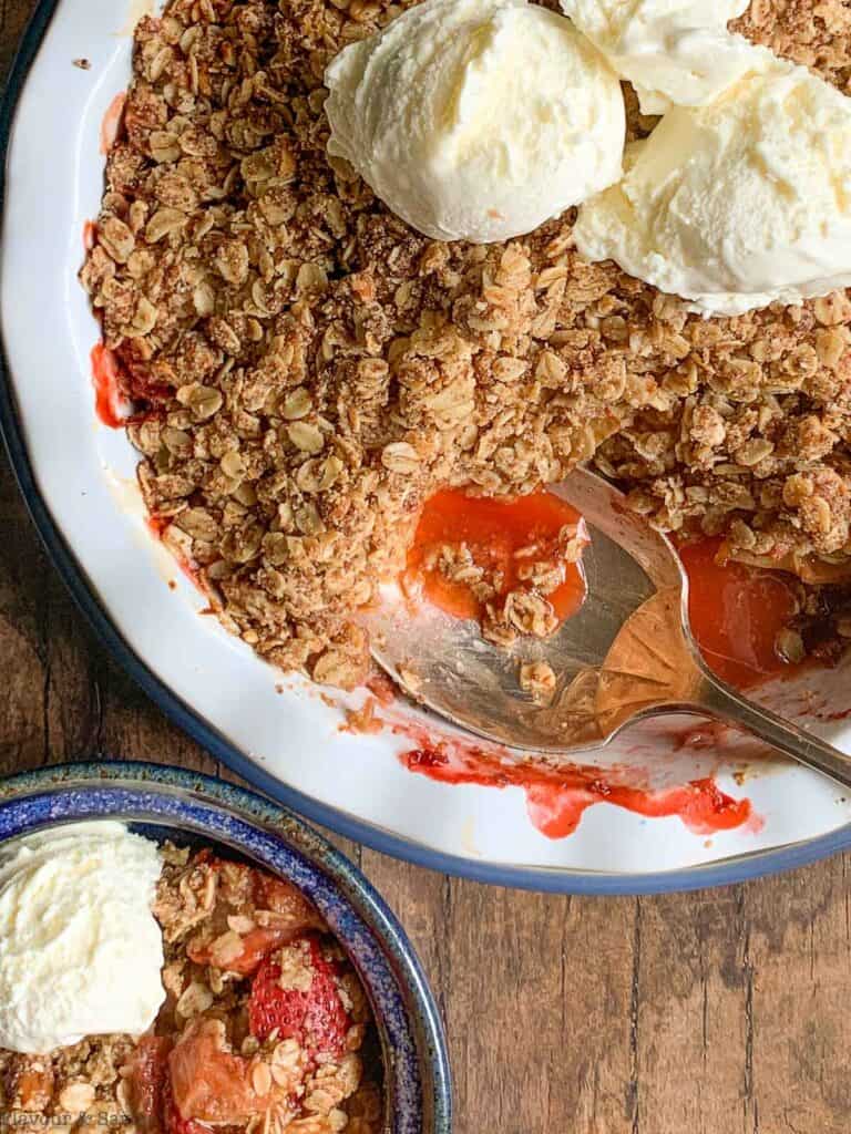 A round dish with strawberry rhubarb crisp and ice cream