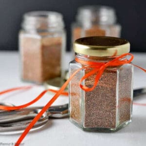 A small jar of taco seasoning mix tied with an orange ribbon.