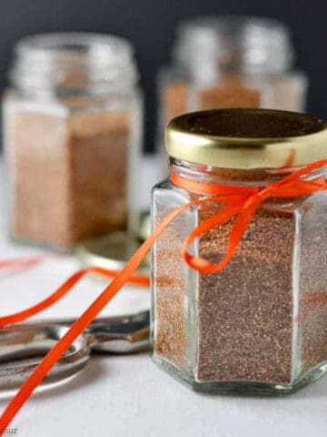 A small jar of taco seasoning mix tied with an orange ribbon.