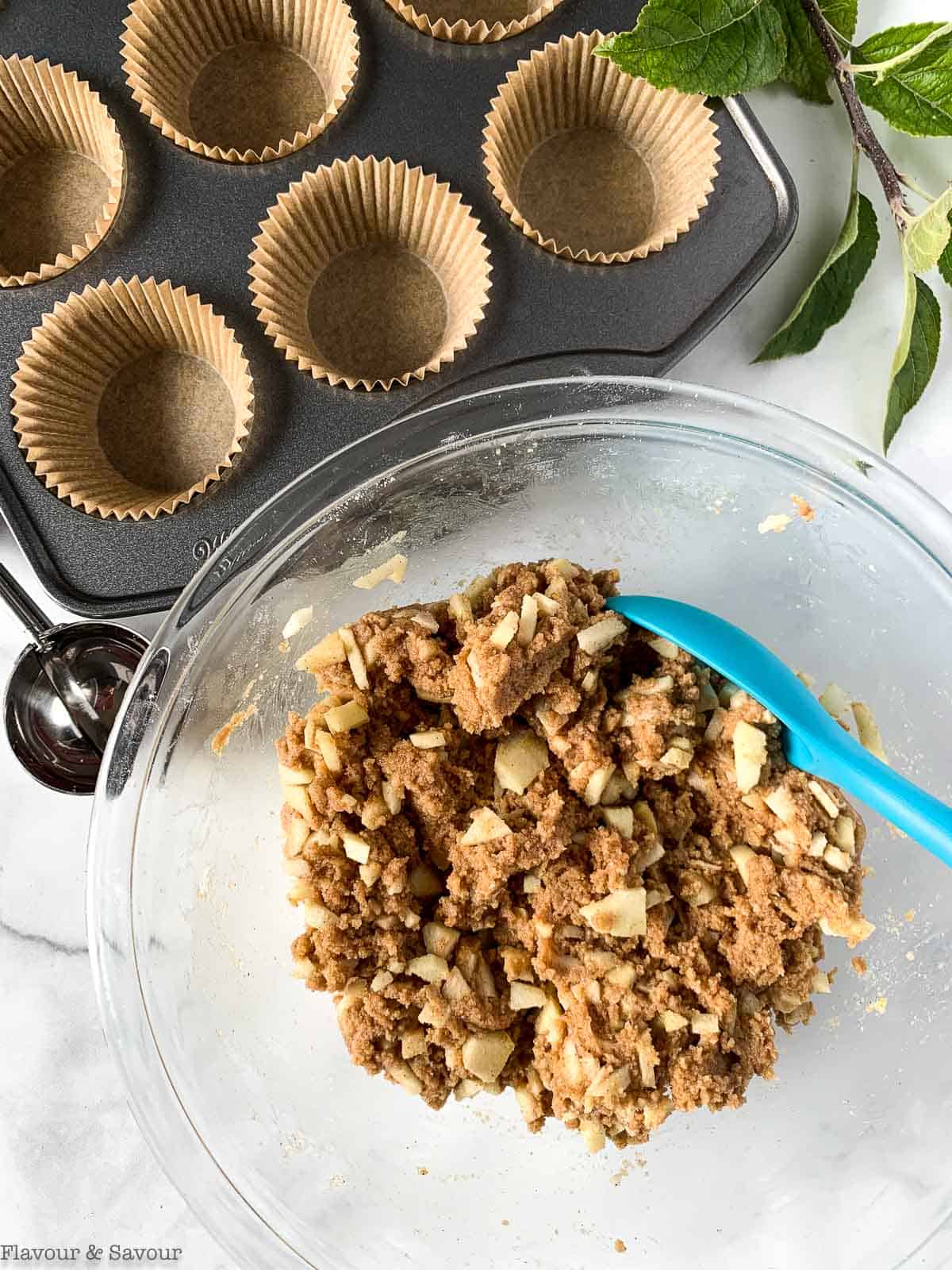 Adding chopped apples to thick apple muffin batter.