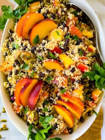 a bowl of quinoa black bean salad with peaches and pumpkin seeds