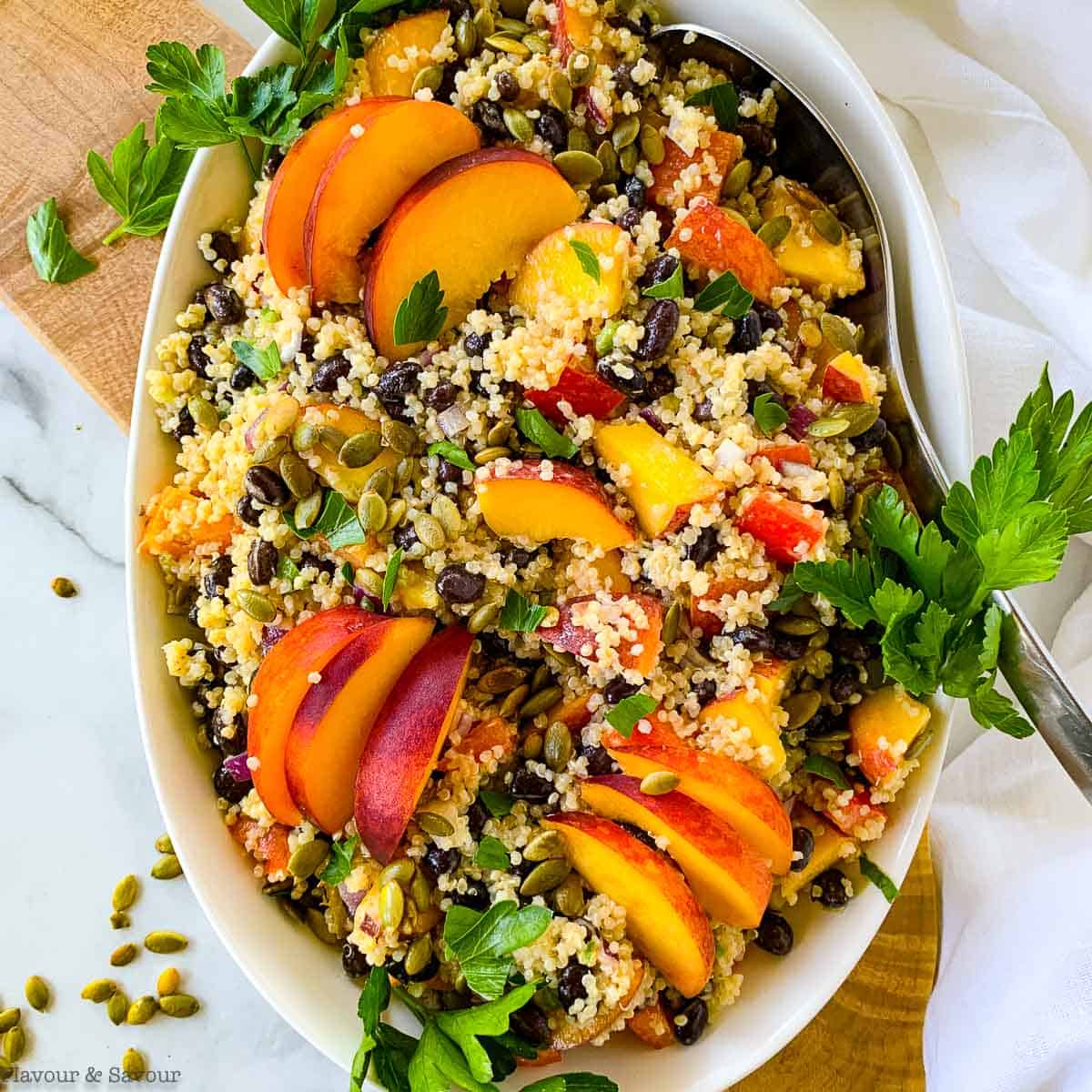 a bowl of quinoa black bean salad with peaches and pumpkin seeds