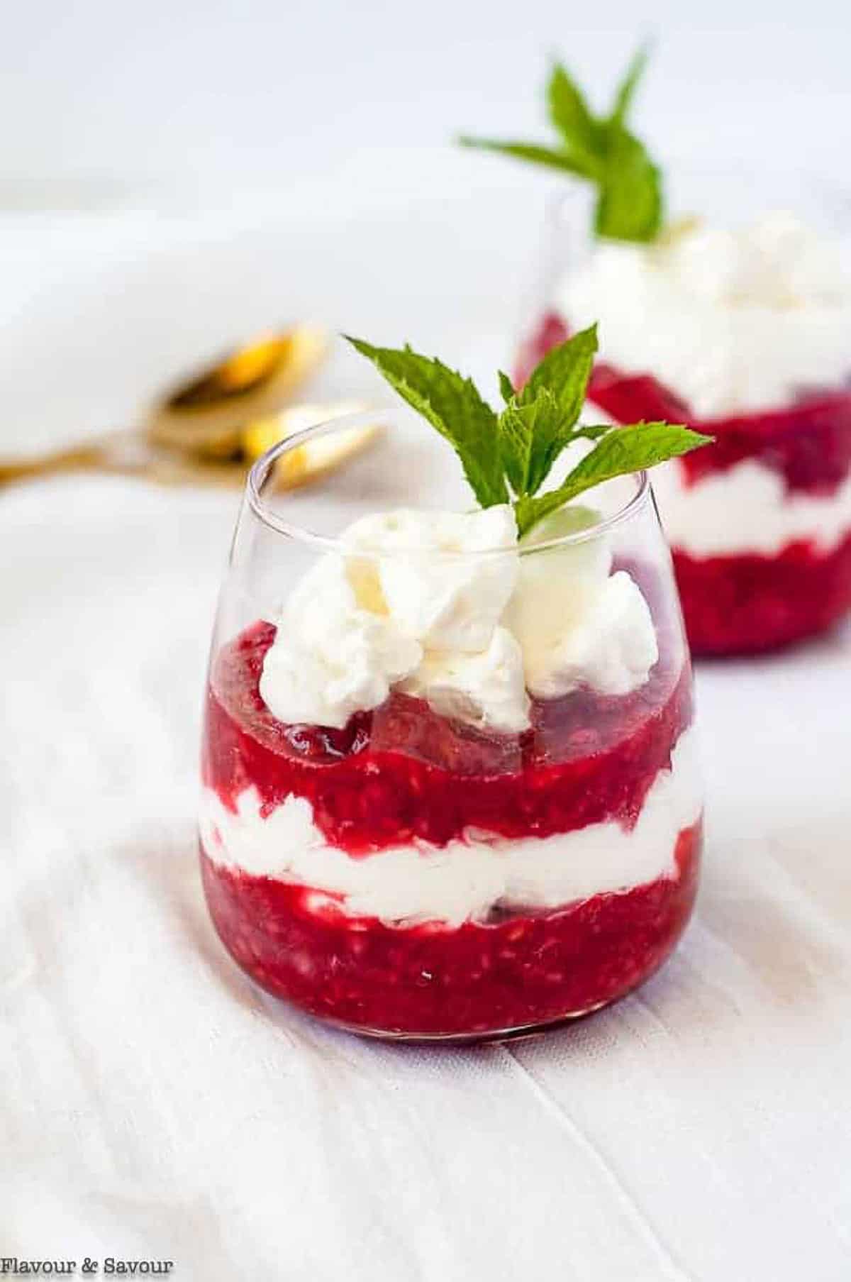 A glass of raspberry rhubarb fool garnished with a mint leaf.