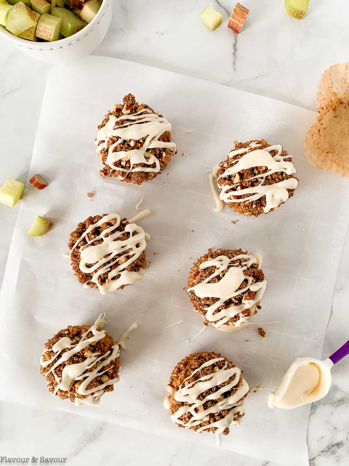 Rhubarb Streusel Muffins with vanilla glaze on a sheet of parchment paper.