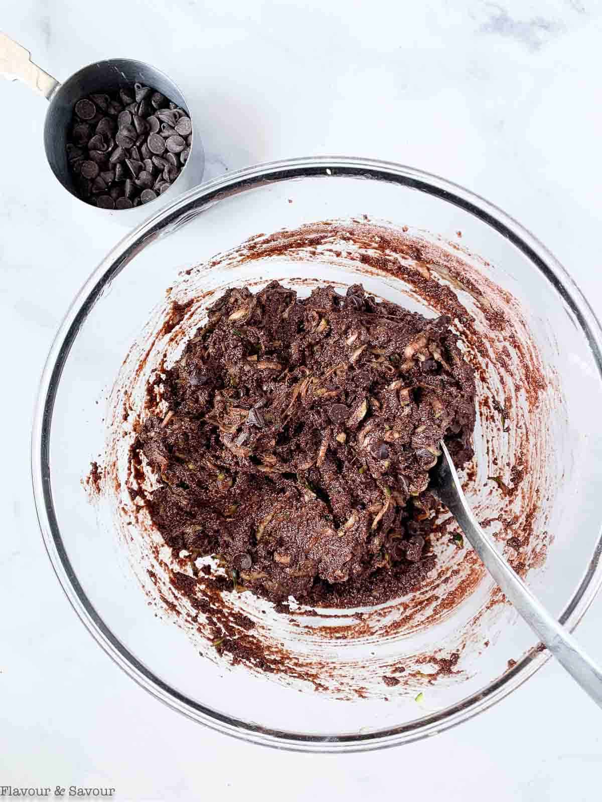 Stirring chocolate chips to zucchini bread batter.