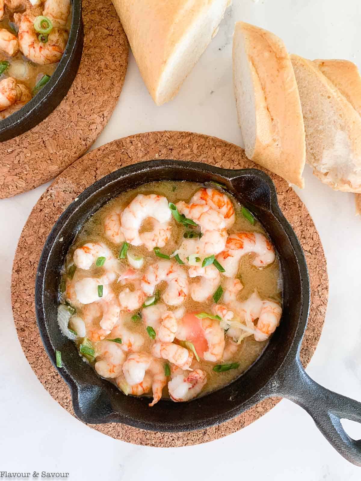 Gin-gingered prawns in a small cast iron skillet with baguette slices.