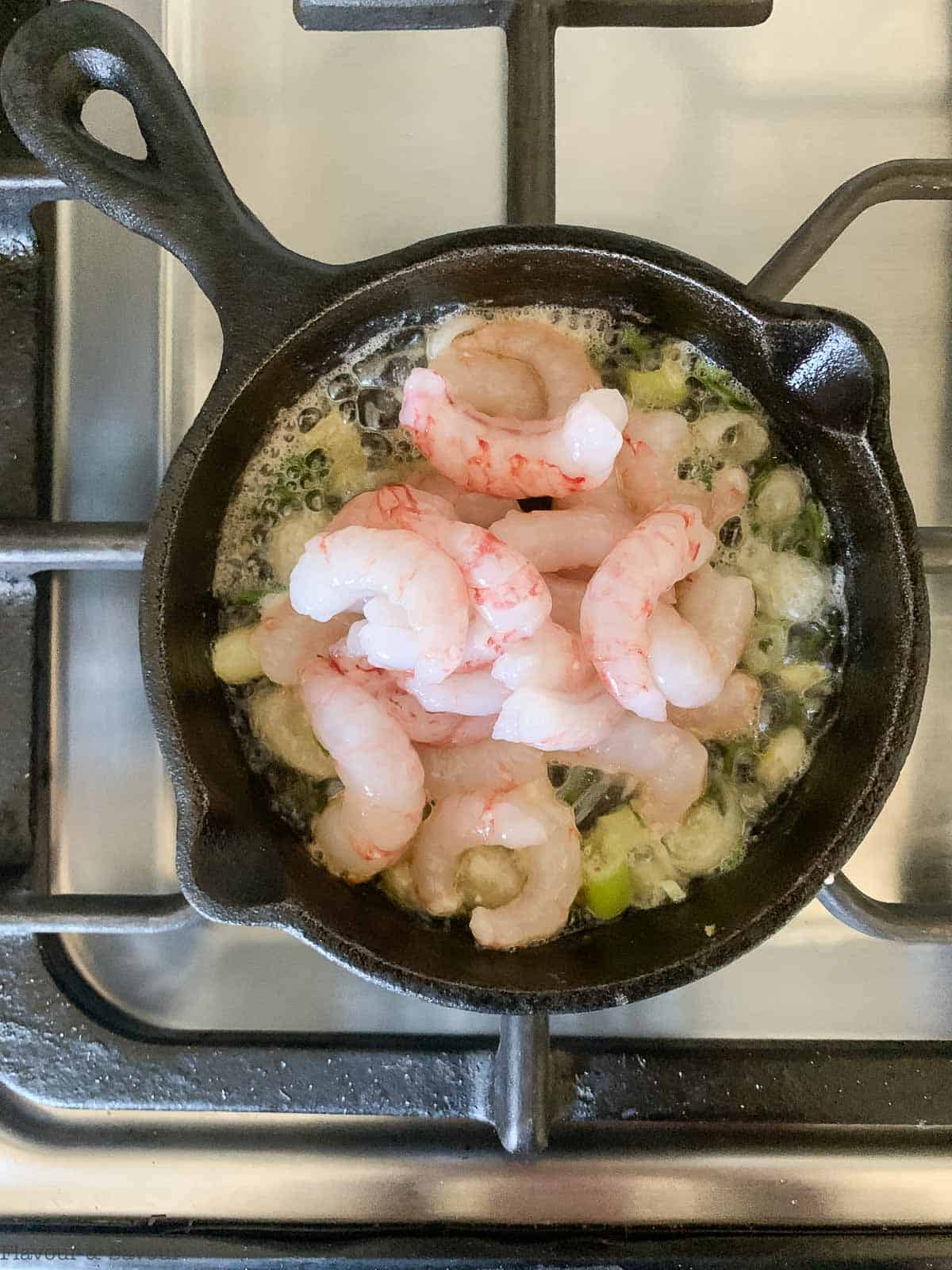 a skillet with butter, green onions and shrimp