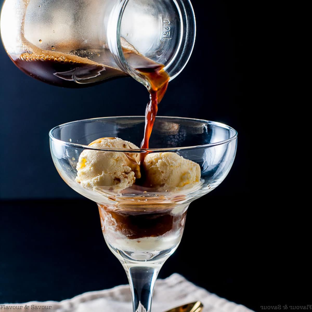 Pouring espresso on a dessert glass full of vanilla ice cream