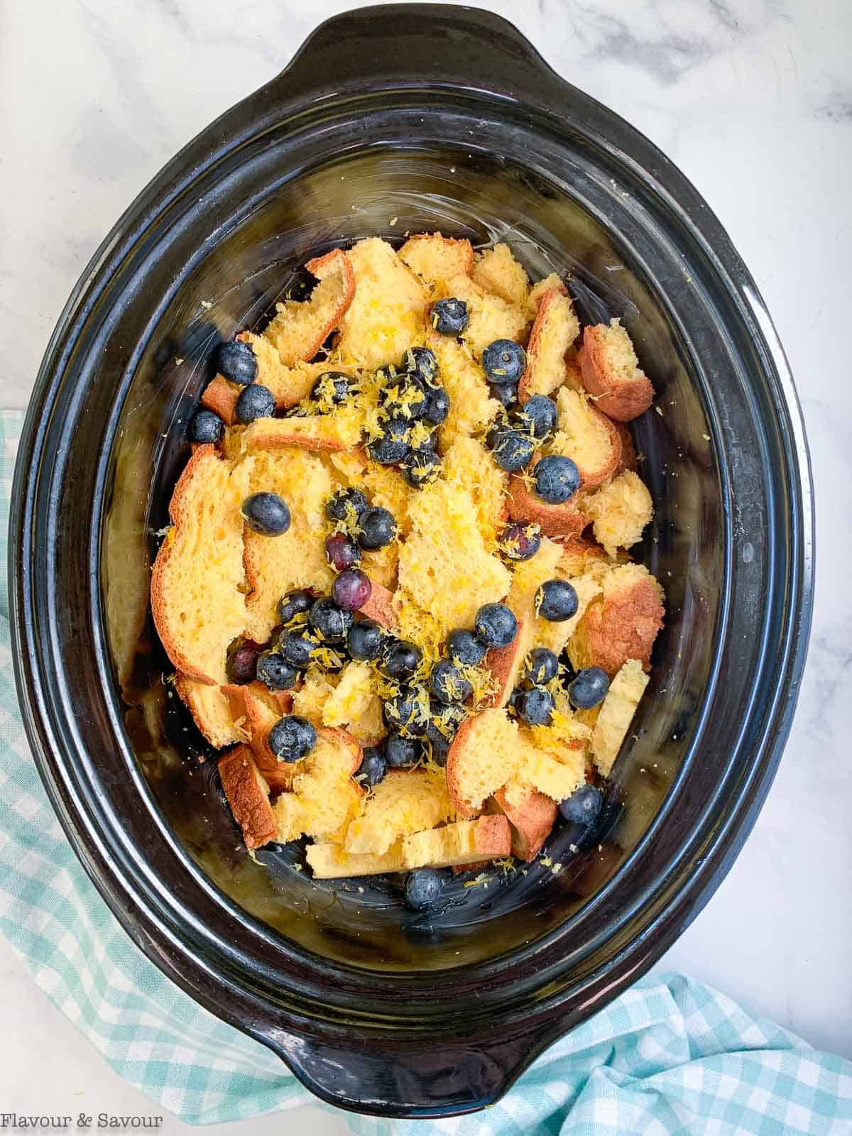 adding bread to slow cooker for blueberry French toast
