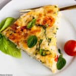 a slice of Cheesy Zucchini Quiche with fresh cherry tomatoes