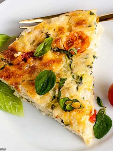 a slice of Cheesy Zucchini Quiche with fresh cherry tomatoes